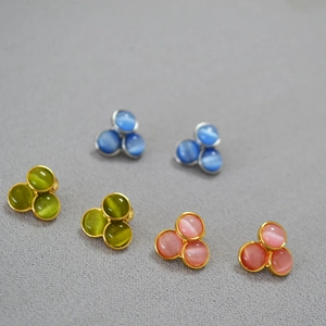 Detailed close-up of three pairs of cat-eye stone flower stud earrings in various colors