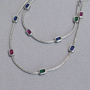 Detail of silver chain necklace featuring rectangular blue, pink and green gemstones