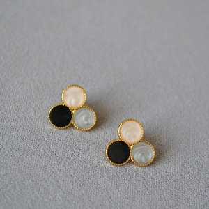 Close-up of tricolor round stud earrings featuring marble textures and gold milgrain edges