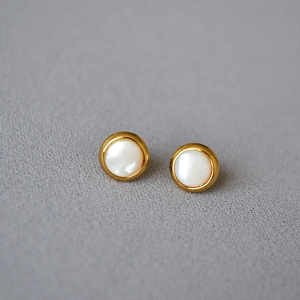 Détail de boucles d'oreilles en laiton doré avec incrustation de nacre blanche