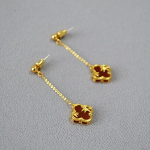 Detailed macro shot of vintage gold bamboo clover earrings with red agate inlays