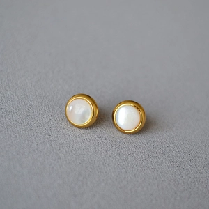 Détail de boucles d'oreilles rondes en laiton doré avec nacre blanche naturelle incrustée