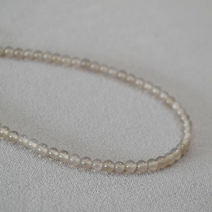 Vue macro de perles d'agate gris fumé translucides sur un collier minimaliste