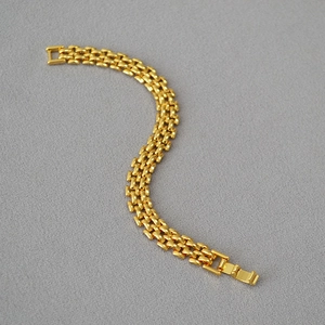 Detailed top view of gold multi-row link bracelet with folding clasp on dark texture