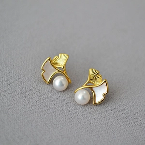 Detail view of gold ginkgo leaf earrings with mother of pearl inlay and round pearls