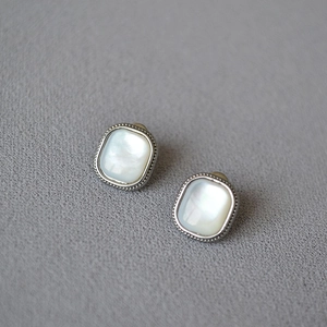 Vintage silver square stud earrings with mother of pearl and milgrain edges on gray fabric