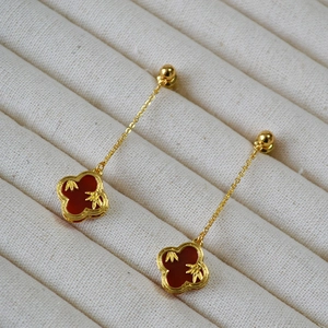 Detail of clover earrings with red agate inlay and golden bamboo leaf motif on velvet