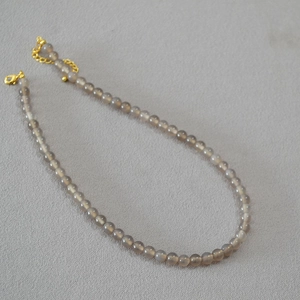 Détail de perles d'agate gris fumé translucides avec fermoir mousqueton doré réglable
