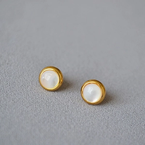 Gros plan de boucles d'oreilles minimalistes en laiton doré avec nacre blanche ronde