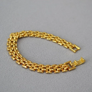 Detailed macro view of four-row polished gold-plated chain bracelet with folding clasp