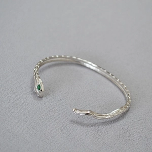 Bracciale a serpente minimalista in argento con occhi di gemma verde e trama a squame