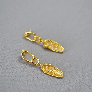 Golden irregular chain texture leaf earrings with pearls and zircons on grey fabric