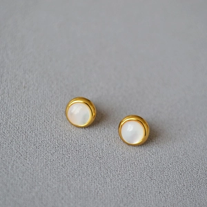 Gros plan d'élégantes boucles d'oreilles en laiton doré avec incrustation de nacre