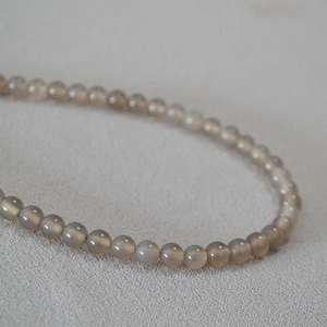 Gros plan sur les perles d'agate gris fumé translucides avec une surface polie sur tissu