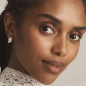 Close-up of golden irregular lava earring with sparkling zircon on model ear