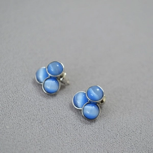 Macro shot of blue cat eye stone earrings in a triangular three-ball minimalist setting