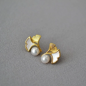 Detail view of gold ginkgo leaf earrings with mother-of-pearl inlay and freshwater pearls