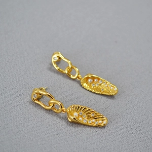 Detailed close-up of gold shell drop earrings with inlaid pearls and sparkling crystals