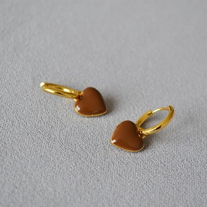 Détail macro de boucles d'oreilles cœur en émail rouge avec crochets dorés élégants