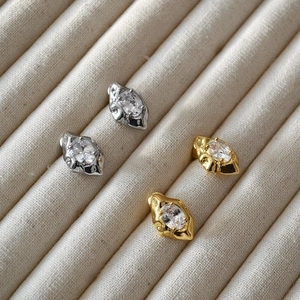 Macro detail of irregular lava texture earrings with zircon in gold and silver finish