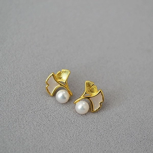 Macro detail of gold-plated ginkgo leaf earrings with mother-of-pearl and freshwater pearl