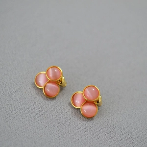 Detailed macro view of pink cat eye clover earrings with gold plating and silver needles
