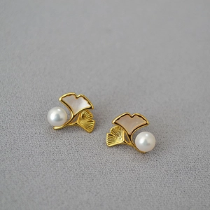 Macro shot of ginkgo leaf earrings with fresh water pearl and brushed gold finish