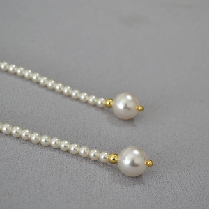 Détail d'un long collier de perles élégant montrant des perles dégradées et des touches dorées