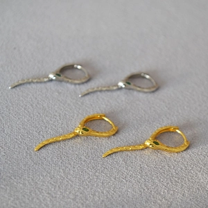 Détail d'une boucle d'oreille serpent avec yeux verts et texture d'écailles