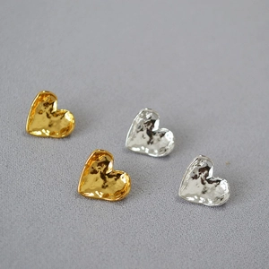 Detail view of heart-shaped earrings with hammered texture in gold and silver finish