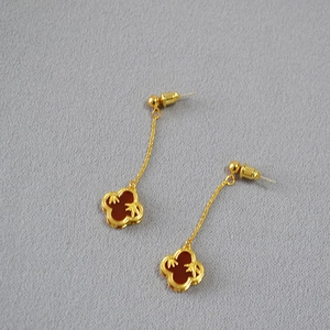 Macro shot of long clover earrings with red agate and gold bamboo leaf patterns
