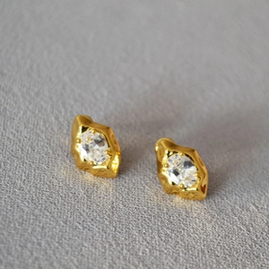 Macro shot of irregular lava design gold earrings with sparkling cubic zirconia crystals