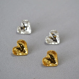 Detailed macro view of gold and silver heart stud earrings with irregular hammered texture