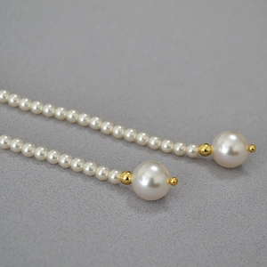 Détail de collier long en perles de style français avec des perles dorées élégantes