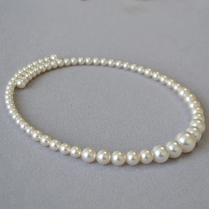 Elegant French style choker with gradient round high-gloss pearls on gray textured fabric