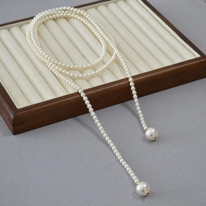 Détail d'un long collier de perles avec grandes perles d'extrémité sur bois