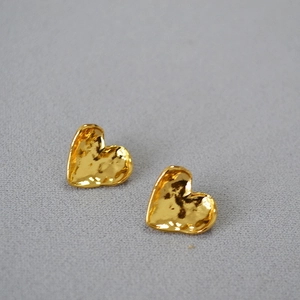 Macro view of golden heart studs featuring unique hammered texture and vintage finish