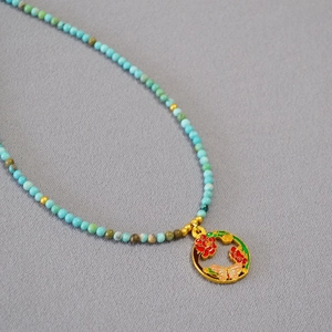 Collier artisanal perlé de turquoise avec pendentif papillon en émail doré élégant