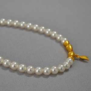 Détail du collier vintage en laiton style bambou avec perles blanches et accents dorés