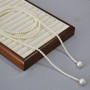 Détail d'un long collier de perles avec fermoir doré sur présentoir à bijoux en bois