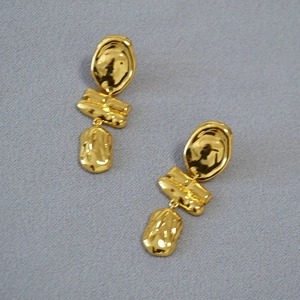 Macro detail of gold irregular baroque earrings with artistic molten metal texture