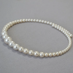 Detail of elegant gradient faux pearl choker necklace with high luster on grey fabric