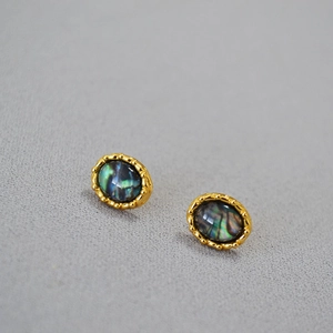 Detail of oval brass earrings with rainbow abalone shell inlay and beaded gold edges