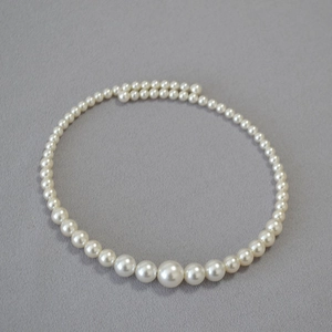 Detailed macro view of gradient faux pearl necklace featuring polished round white pearls