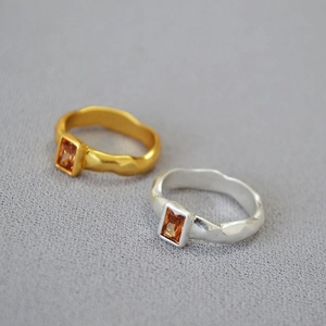 Detail view of irregular hammered rings in gold and silver with brown zircon crystals