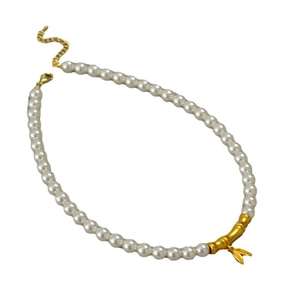 Collier de perles vintage avec pendentifs bambou dorés sur fond blanc épuré