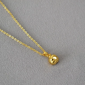 Detail of 18k gold plated brass necklace featuring a polished apple-shaped 3D pendant
