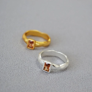 Detail of hammered metal texture rings with rectangular amber zircon in gold and silver
