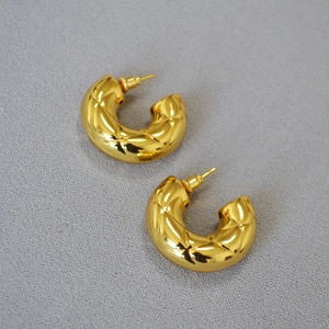 Detailed view of gold-plated hollow C-shaped earrings with quilted rhombic texture