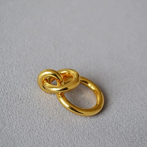 Detailed view of intertwined double-loop gold earrings with a high-polished finish